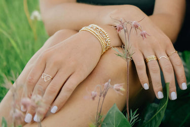 Wholesale Jewelry Retailer Application Banner Close-up of hands with gold rings and bracelets on a natural background